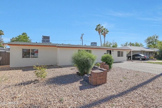 ranch-style house featuring fence, cooling unit, driveway, and stucco siding