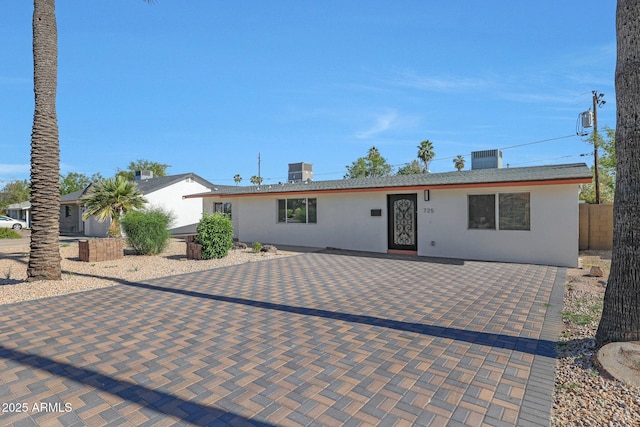 ranch-style house featuring central AC, fence, and stucco siding