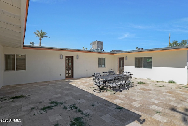 rear view of property with a patio area, stucco siding, and outdoor dining area