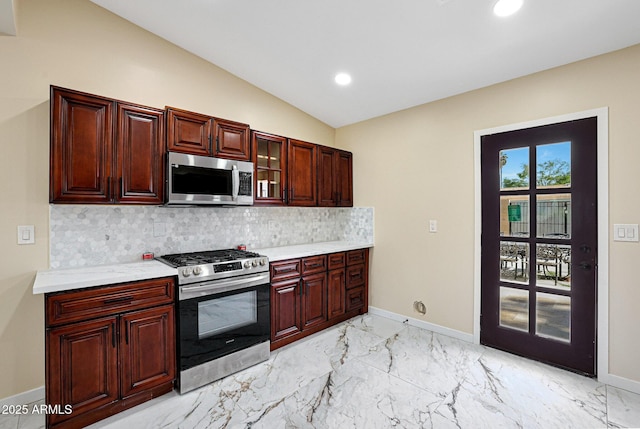 kitchen with backsplash, baseboards, light countertops, and stainless steel appliances
