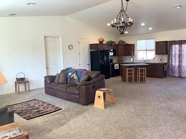 living area featuring lofted ceiling, visible vents, and a chandelier