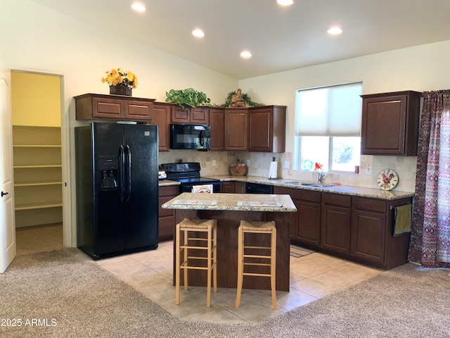 kitchen with tasteful backsplash, a center island, dark brown cabinetry, vaulted ceiling, and black appliances