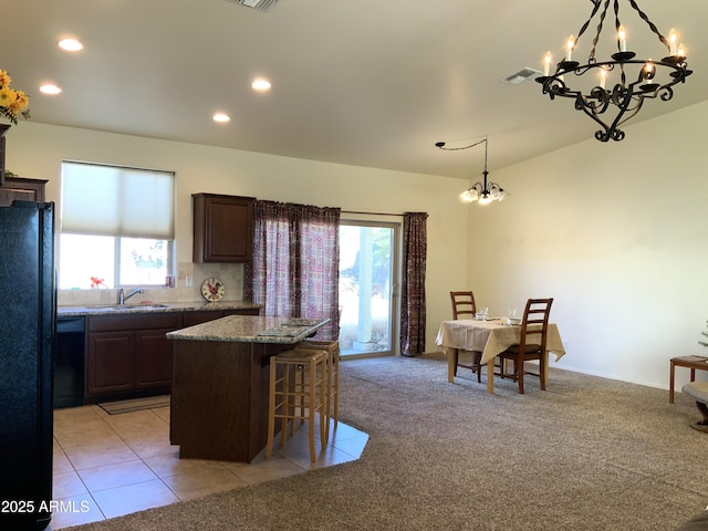 kitchen featuring an inviting chandelier, a sink, light carpet, a kitchen breakfast bar, and a center island