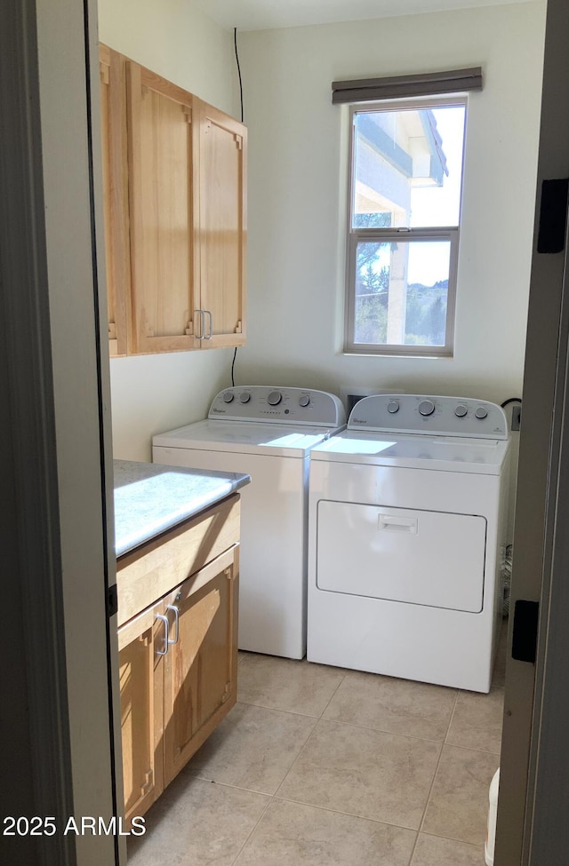 washroom with cabinet space, light tile patterned flooring, and washer and clothes dryer