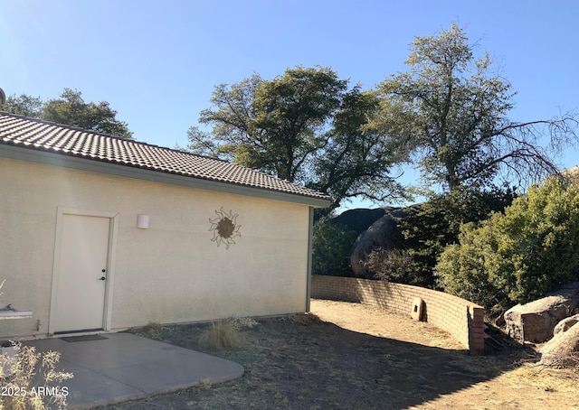 view of side of home with a tile roof and stucco siding