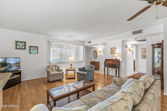 living room featuring a textured ceiling, ceiling fan, and light hardwood / wood-style flooring