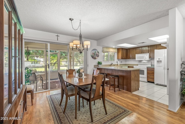 dining area featuring light wood-type flooring, an inviting chandelier, and a textured ceiling