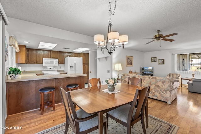 dining space featuring a textured ceiling, ceiling fan with notable chandelier, and light hardwood / wood-style flooring