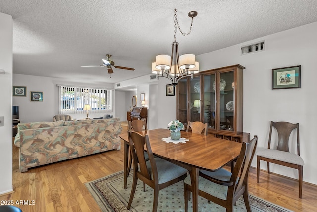 dining room featuring a textured ceiling, ceiling fan with notable chandelier, and light hardwood / wood-style flooring