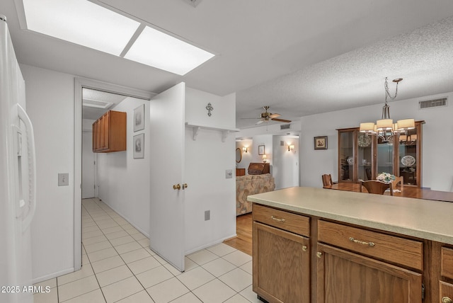 kitchen with ceiling fan with notable chandelier, a textured ceiling, decorative light fixtures, white refrigerator with ice dispenser, and light tile patterned flooring