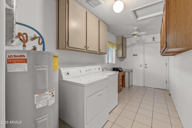 clothes washing area featuring electric water heater, separate washer and dryer, a textured ceiling, light tile patterned floors, and cabinets