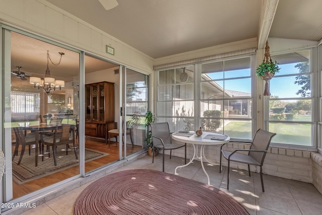 sunroom / solarium with a wealth of natural light and ceiling fan with notable chandelier