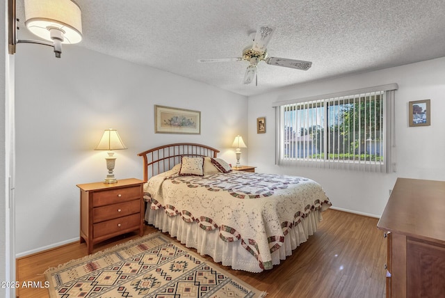 bedroom with ceiling fan, hardwood / wood-style floors, and a textured ceiling