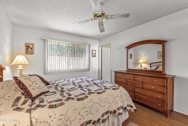 bedroom with ceiling fan, hardwood / wood-style floors, and a textured ceiling