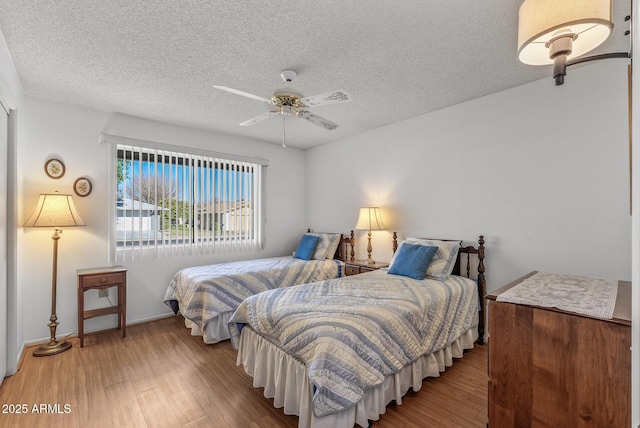 bedroom with light wood-type flooring, ceiling fan, and a textured ceiling