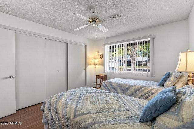 bedroom with a textured ceiling, a closet, wood-type flooring, and ceiling fan