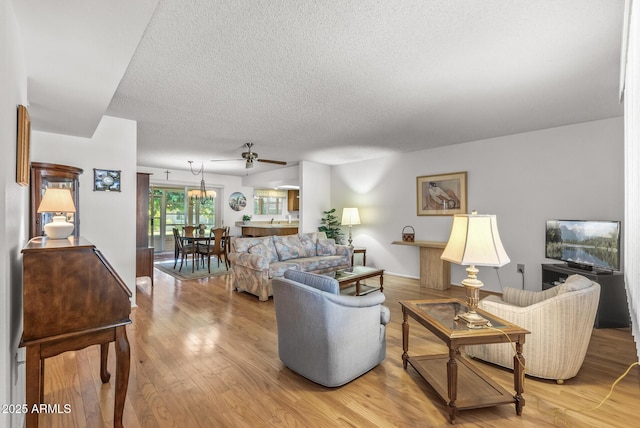 living room with ceiling fan, wood-type flooring, and a textured ceiling