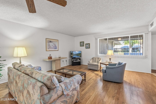 living room featuring ceiling fan, a textured ceiling, and light hardwood / wood-style flooring