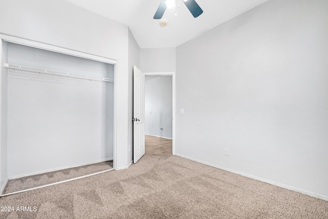 unfurnished bedroom featuring light colored carpet, ceiling fan, vaulted ceiling, and a closet