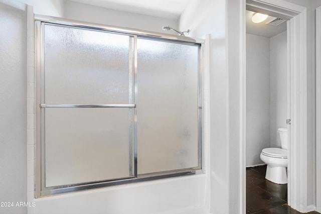 bathroom with combined bath / shower with glass door and toilet