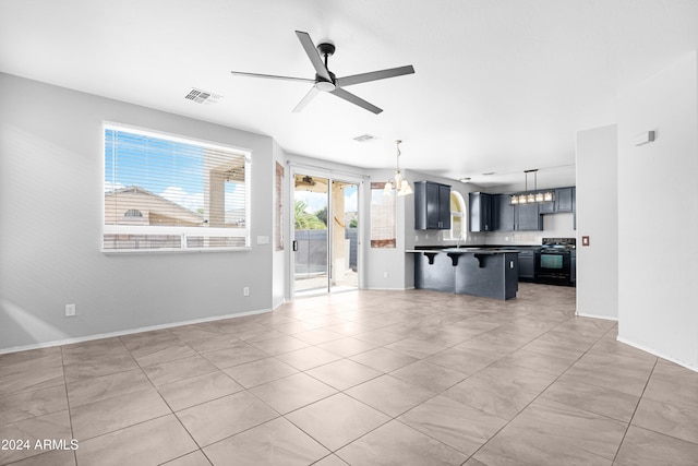 unfurnished living room with ceiling fan with notable chandelier and light tile patterned floors