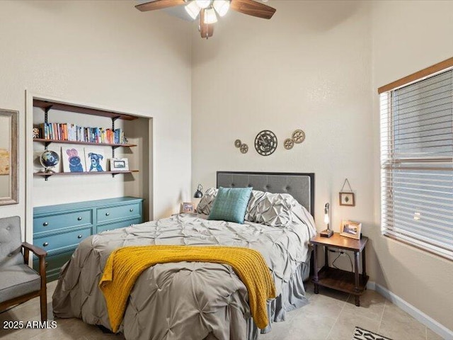 bedroom with light tile patterned floors, a high ceiling, and a ceiling fan