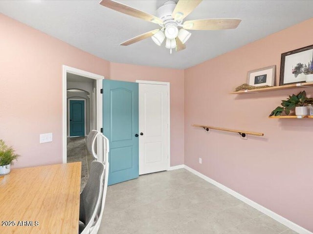 unfurnished office featuring ceiling fan and baseboards