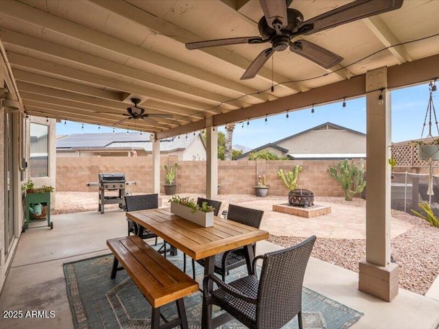 view of patio with a ceiling fan, a fenced backyard, outdoor dining space, and an outdoor fire pit