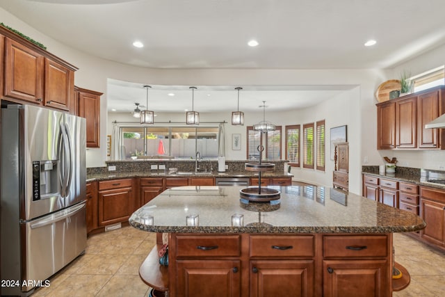 kitchen with hanging light fixtures, a kitchen island, sink, and stainless steel appliances