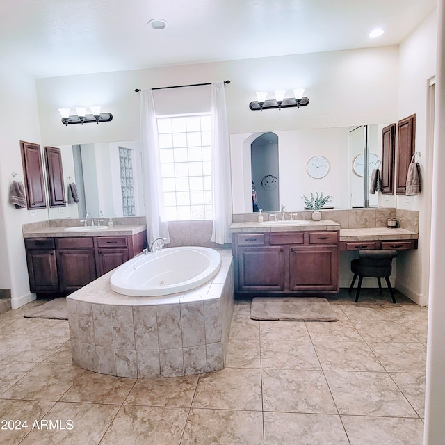 bathroom featuring an inviting chandelier, tile patterned flooring, tiled bath, and vanity