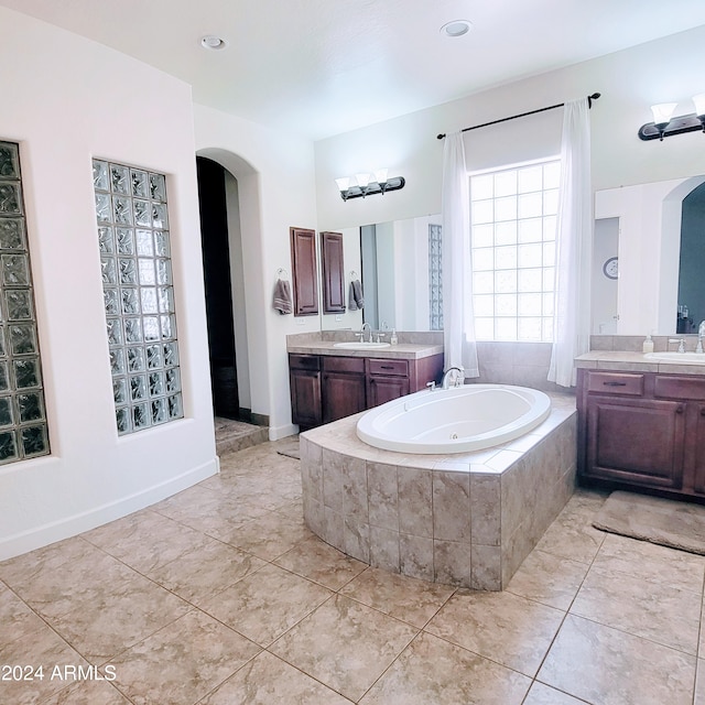 bathroom with a relaxing tiled tub, tile patterned floors, and vanity