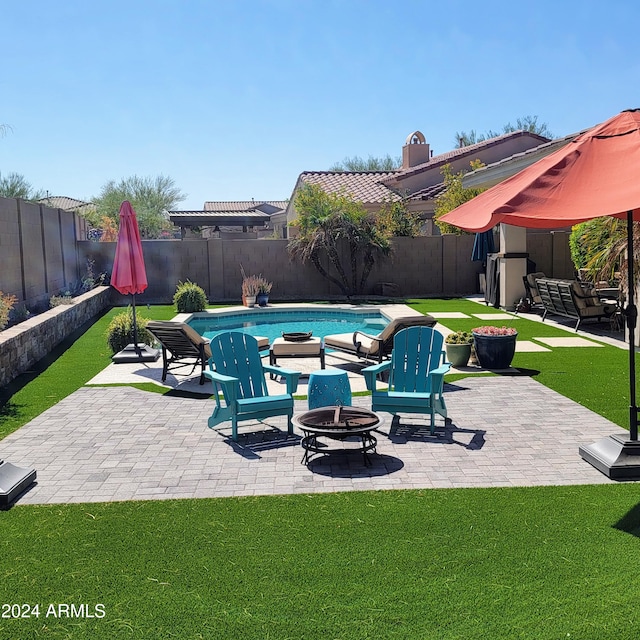 view of pool featuring a yard, a patio area, and a fire pit