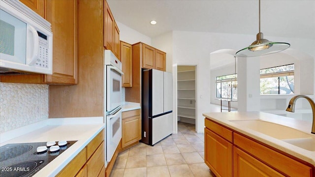 kitchen with sink, tasteful backsplash, decorative light fixtures, light tile patterned floors, and white appliances