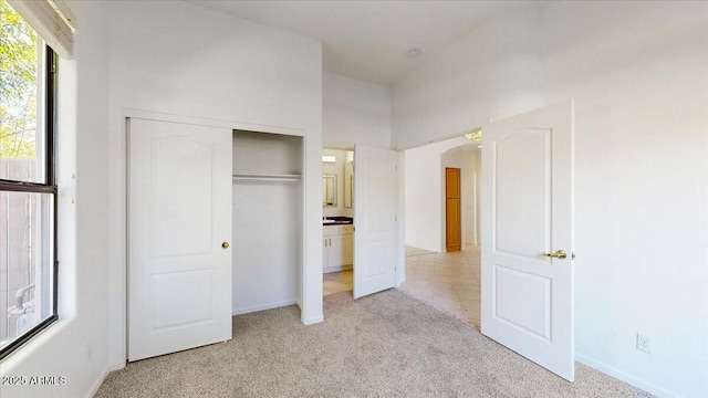 unfurnished bedroom with light colored carpet and a closet