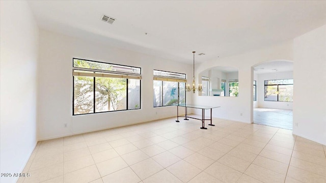 tiled empty room featuring a chandelier