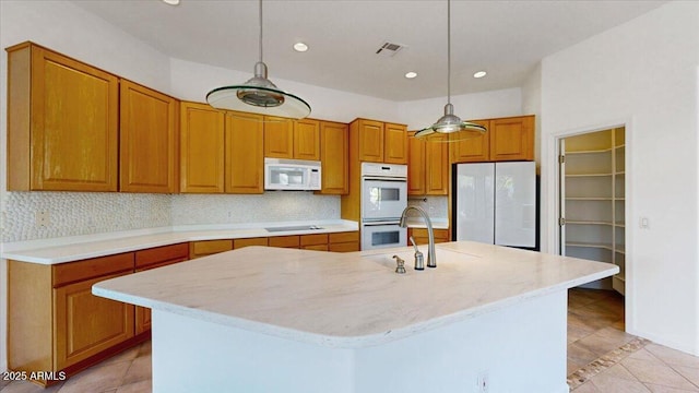 kitchen with pendant lighting, white appliances, an island with sink, and backsplash