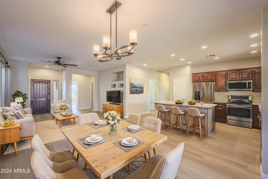 dining space featuring ceiling fan with notable chandelier and light hardwood / wood-style floors