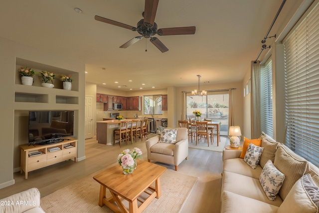 living room with light hardwood / wood-style floors and ceiling fan with notable chandelier