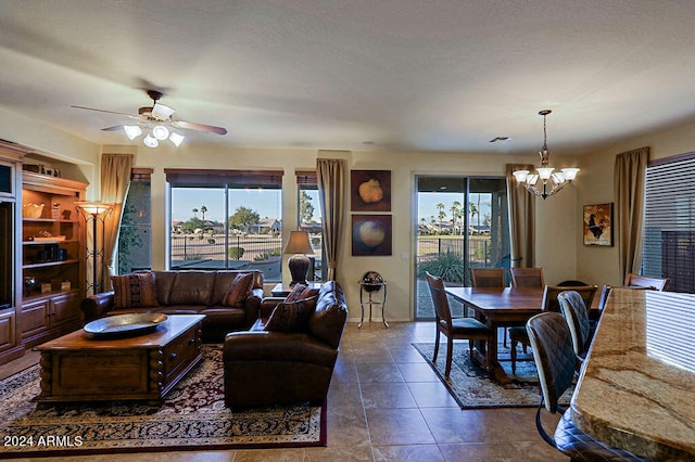 tiled living room with plenty of natural light and ceiling fan with notable chandelier