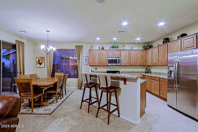 kitchen featuring hanging light fixtures, a breakfast bar, a center island, a chandelier, and appliances with stainless steel finishes