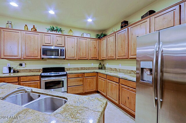 kitchen featuring light stone countertops, appliances with stainless steel finishes, and sink