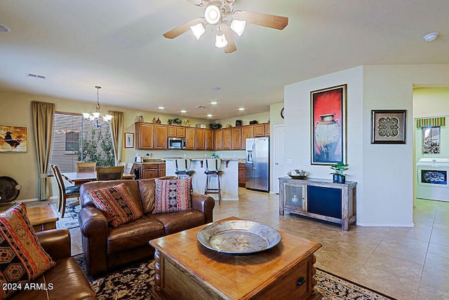 living room featuring washer / dryer, light tile patterned floors, and ceiling fan with notable chandelier