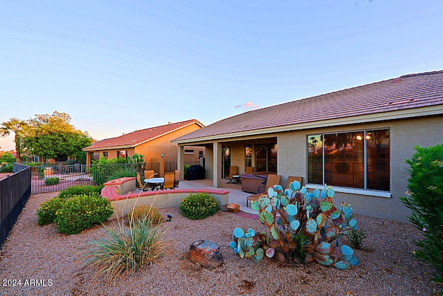 back house at dusk featuring a patio area