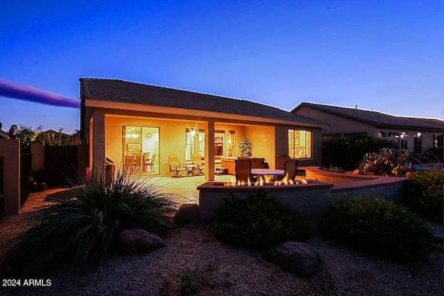 back house at dusk featuring a patio area