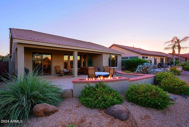 back house at dusk featuring a patio area