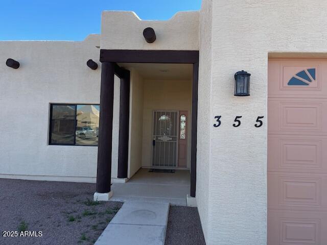 view of exterior entry with stucco siding and a garage