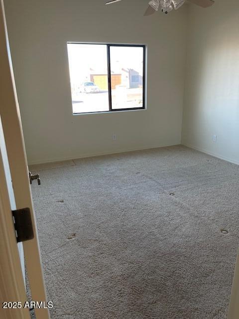 carpeted spare room featuring a ceiling fan