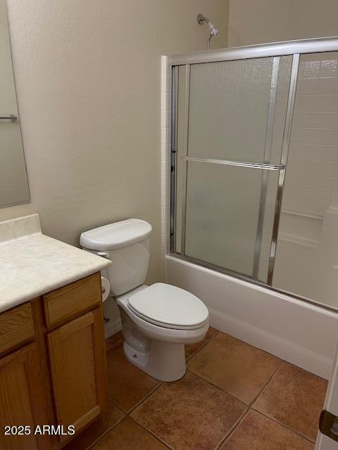 full bath featuring combined bath / shower with glass door, toilet, vanity, and tile patterned floors