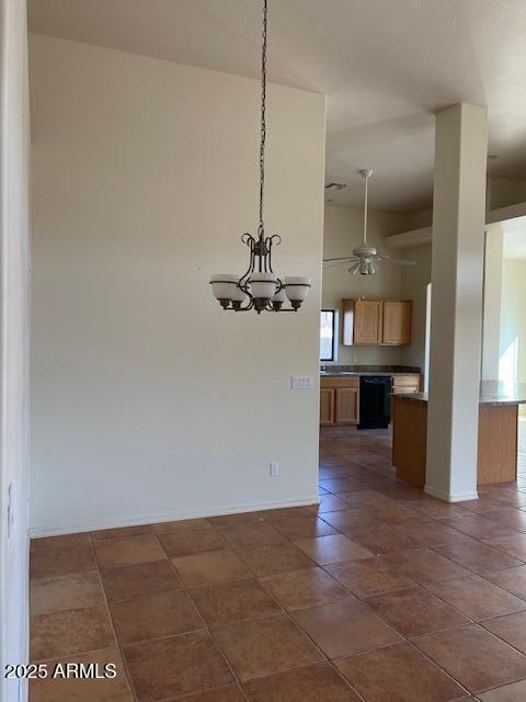 unfurnished dining area with dark tile patterned floors, ceiling fan with notable chandelier, and baseboards