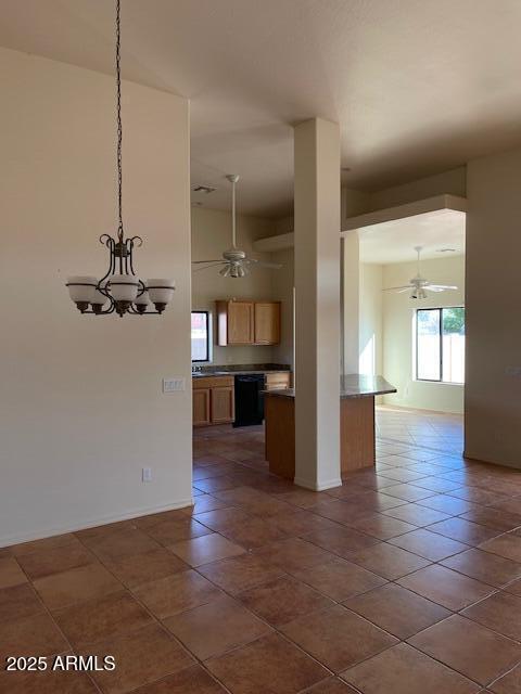 interior space featuring baseboards, dark tile patterned floors, and ceiling fan with notable chandelier